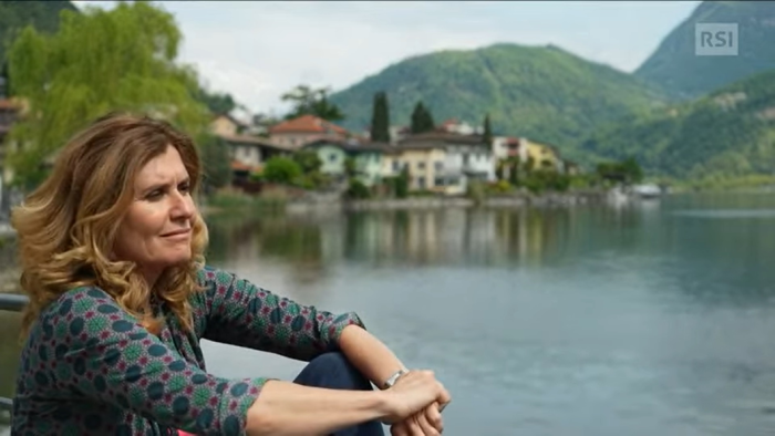 foto della scultrice che contempla il paesaggio sulla riva di un lago