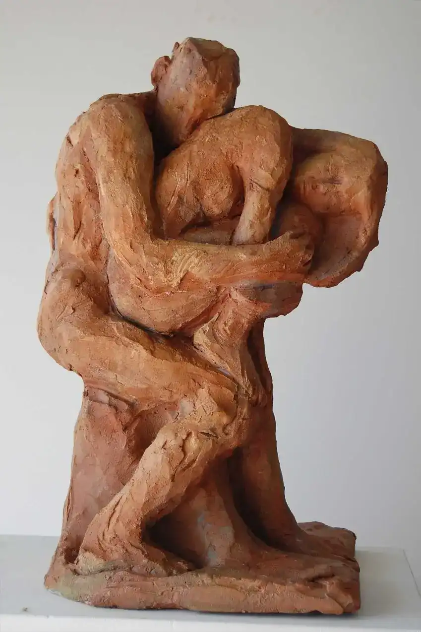 Scultura in terracotta: un uomo protegge amorevolmente con il proprio corpo quello di una donna.